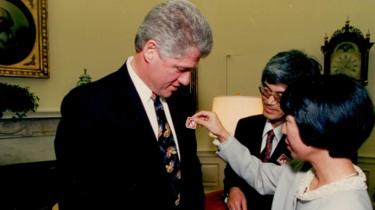 Mieko (centro) y Masa (derecha) poniéndole un adhesivo relacionado con el control de armas al entonces presidente Bill Clinton.