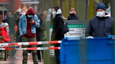 mennesker uden for en bygning i Tyskland, der venter på at blive testet for Covid-19