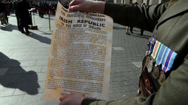 Un soldato irlandese tiene una copia della Proclamazione della Repubblica irlandese del 1916 fuori dal General Post Office (GPO), la scena della rivolta di Pasqua del 1916, a Dublino il 27 marzo, 2016 come parte di un programma di eventi commemorativi per segnare il 100° anniversario della Rivolta di Pasqua