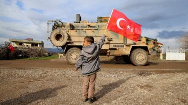 et foto taget fra Tyrkiets Hatay-provins viser børn hilser soldater med tyrkiske flag under tyrkisk militærkonvoj bestående af cirka 300 pansrede personelbærere er på vej mod observationspunkter i Syriens Idlib, den 08. februar 2020 i Hatay, Tyrkiet's Hatay province shows children greets soldiers with Turkish flags during Turkish military convoy consisting of approximately 300 armoured personnel carriers are on the way towards observation points in Syria's Idlib, on February 08, 2020 in Hatay, Turkey