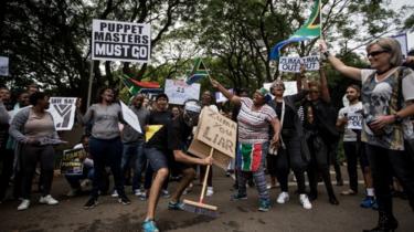 Demonstrators holding signs such as "Puppet masters must go" "Zuma you liar"