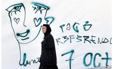 A Romanian Orthodox nun passes by a graffiti symbolizing the crying face of a LGBT community member on 5 Oct