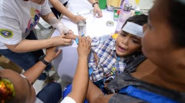 Un operatore sanitario si tratta di un ragazzo affetto da febbre dengue in Cabatuan, Filippine lo scorso mese