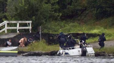 オスロの南西約40kmにあるウトヤ島で銃撃があり、人々が身を隠す間に武装警察が銃口を向ける（2011年7月22日）