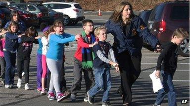 Students exit Sandy Hook Elementary school with help from a police officer
