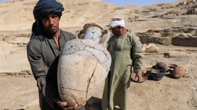 A person holds an unearthed pot at the site of the 'Lost Golden City', Egypt