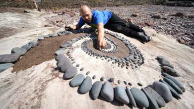 Mark Antony Haden Ford works on an artwork at Eye Cave beach in Dunbar, Scotland, ahead of the European Stone Stacking Championships, on 8 July 2021