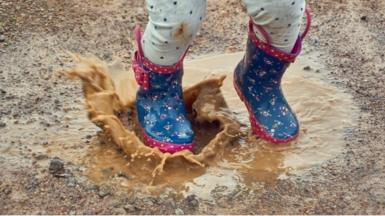 Child splashes in muddy puddle