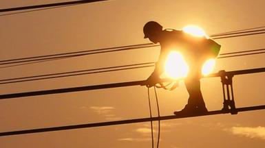 An electrician carries out maintenance work on electric wires of a 500KV transmission line project at sunset in Lianyungang, Jiangsu Province of China on 28 September 2022.