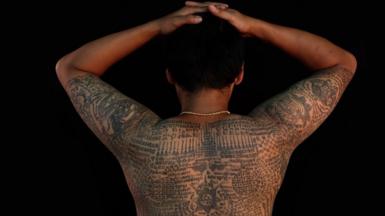 A man showing the tattoos on his back