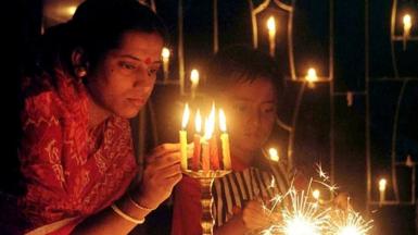 Namita Biswas, a Bengali housewife, lights candles as her son lights sparklers during Diwali in Calcutta, 26 October 2000