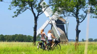 People cycling past a windmill