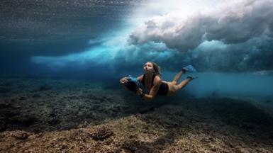 Woman freediving holding camera