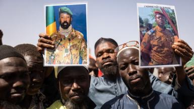 Demonstrators gathering in Ouagadougou to show support on January 25, 2022 to the military hold a picture of Colonel Aissimi Goita (L), the Malian military officer who has served as interim President of Mali since May 24, 2021, and of Lieutenent Colonel Paul-Henri Sandaogo Damiba the leader of the mutiny and of the Patriotic Movement for the Protection and the Restauration (MPSR)