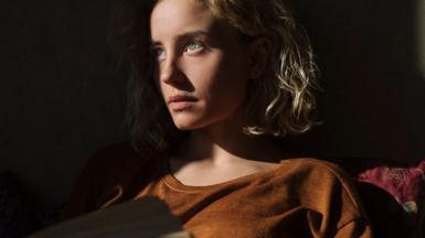 Woman sitting in mostly darkness