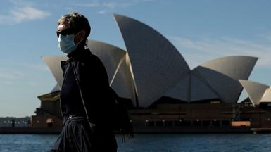 A pedestrian wearing a face mask walks past the Sydney Opera House in Sydney on 13 July 2021