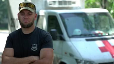 Aleksey Yukov standing next to the white van, marked with a red cross