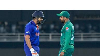 India's Rohit Sharma (L) walks past Pakistan's captain Babar Azam as he arrives to bat during the ICC mens Twenty20 World Cup cricket match between India and Pakistan at the Dubai International Cricket Stadium in Dubai on October 24, 2021.