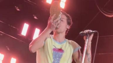 Harry Styles drinking from a shoe on stage