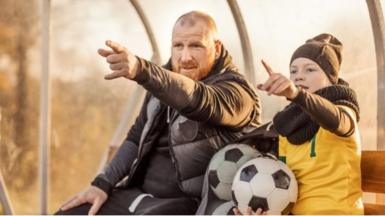 Man and boy holding footballs