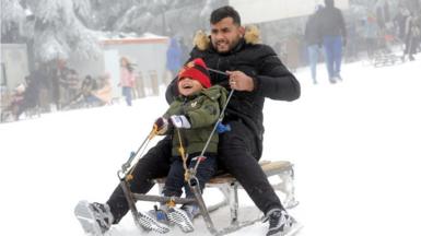 A man and a boy ride a sledge in the snow.