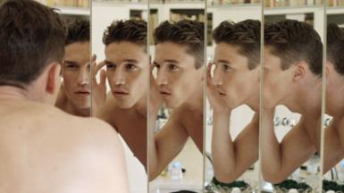 Man looking into multiple mirrors