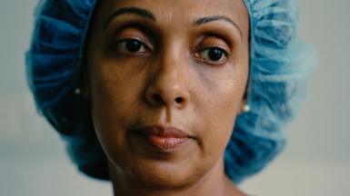 A portrait of an NHS frontline worker wearing scrubs