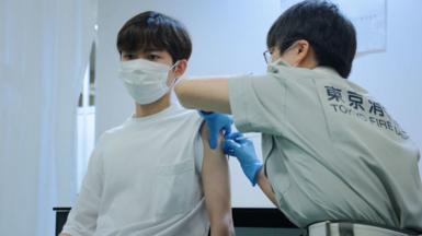 A Tokyo fire brigade staff member (R) administers a dose of the Covid-19 coronavirus vaccine at Aoyama University in Tokyo on August 2, 2021.