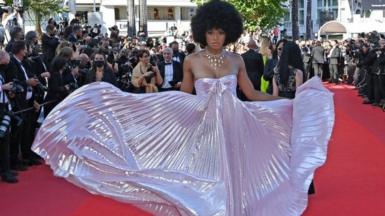 A woman poses in an iridescent dress on the red carpet.