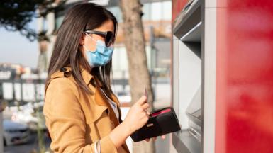 A woman wearing a mask at an ATM