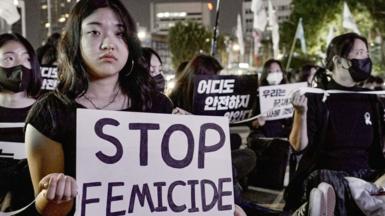 At a protest in Seoul on Thursday night a woman holds a sign saying 'stop femicide'