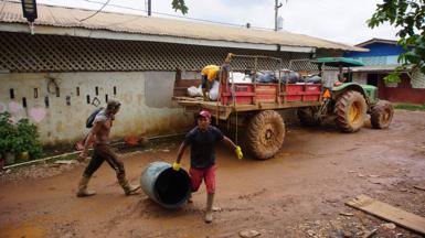 Garbagemen pick up trash in Port Kaituma, Guyana, on September 21, 2022, in front of a garbage truck on a road.