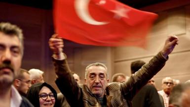 A supporter of President Erdogan waves a Turkish flag at a taxi driver convention