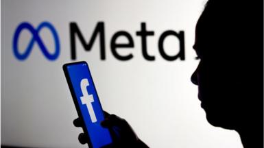In this photo illustration, a woman holds a smartphone with the Facebook logo displayed on the screen with the Meta Platforms logo displayed in the background.