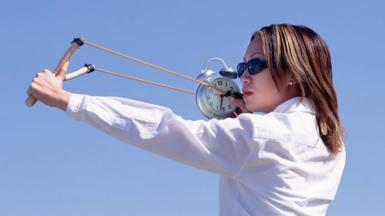 Woman firing a clock from a catapult