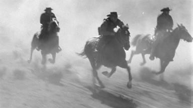 Black and white image of men riding horses
