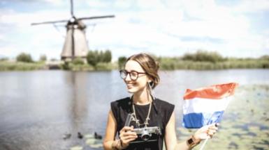 Woman holding Dutch flag near a windmill