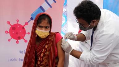 A health worker administers a dose of covid-19 vaccine to a woman during the free covid-19 Vaccination at Swami Shiv Narayan Mandir, B R Camp, Race Course Club in New Delhi.