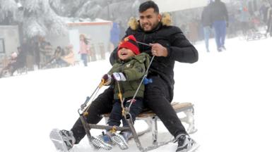 A man and a boy ride a sledge in the snow.