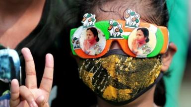 A Trinamool Congress party (TMC) supporter wears glasses with pictures of party supreemo Mamata Bannerjee and shows victory sign as they celebrate after winning an absolute majority in the West Bengal Assembly Election in Kolkata, India, 02 May 2021