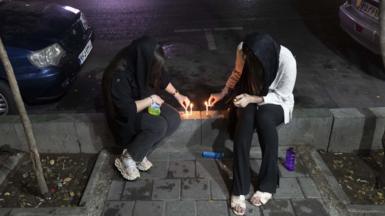 Two Iranian women light candles in Tehran, 8 August 2022.