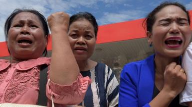 Cambodian women cry outside a convenience store where independent political and social analyst Kem Ley was shot dead in Phnom Penh on 10 July 2016