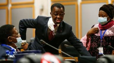 Roger Nkodo Dang (C) speaks with others inside the house following its postponement in Midrand, Johannesburg on June 1, 2021