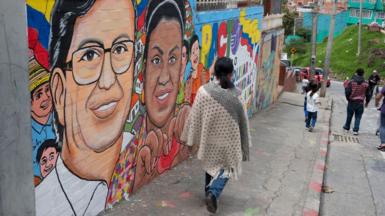 A woman walks past a mural depicting Colombian left-wing presidential candidate for the Historic Pact coalition Gustavo Petro (C) and his vice-presidential candidate Francia Marquez, in Ciudad Bolivar, Bogota, on May 25, 2022.