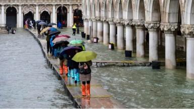 People on a footbridge across floods in Venice