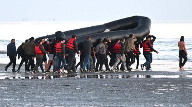 Migrants carry aboat towards the water before they attempt to cross the Channel illegally to Britain, July 2022