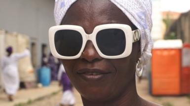 Woman wearing chunky white-rimmed sunglasses and a white headscarf.