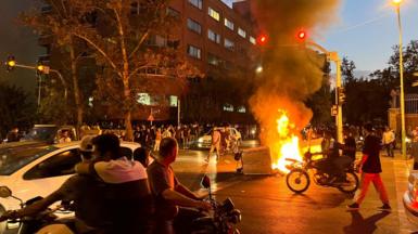 A police motorcycle burns during a protest on a street in Tehran, Iran (19 September 2022)