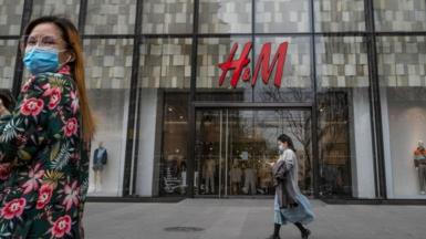 People walk by an H&M clothing store at a shopping area on 30 March 2021 in Beijing, China
