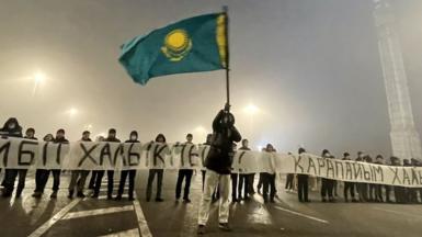 Protesters on Almaty's main square hold a banner saying "we are not terrorists" on 6 January shortly before the shooting